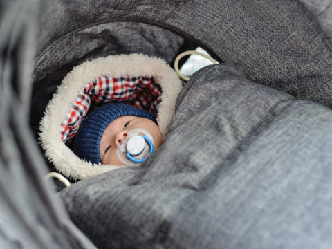 Newborn baby bundled up for winter in a baby carrier