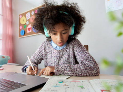 Girl wearing headphones and doing homework