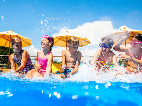 Children play fun with splashes on the side of the pool at the resort; Courtesy of YanLev/Shutterstock