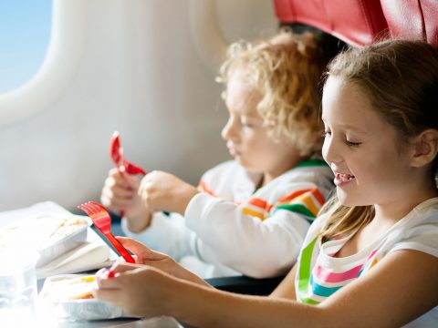 Kids Eating Snacks On A Plane; Courtesy of FamVeld/Shutterstock.com